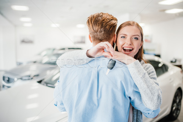 Happy couple holding car key and embracing in dealership salon    Stock photo © LightFieldStudios
