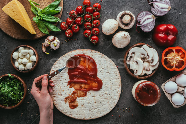 cropped shot of woman spreading ketchup onto pizza dough on concrete surface Stock photo © LightFieldStudios