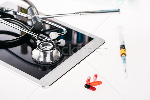 Stock photo: close up view of medical equipment on tablet, insulin syringe and pills on white