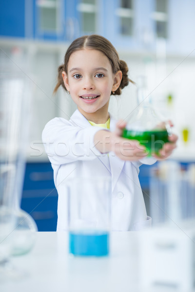Little girl scientist holding flask with reagent and smiling at camera  Stock photo © LightFieldStudios