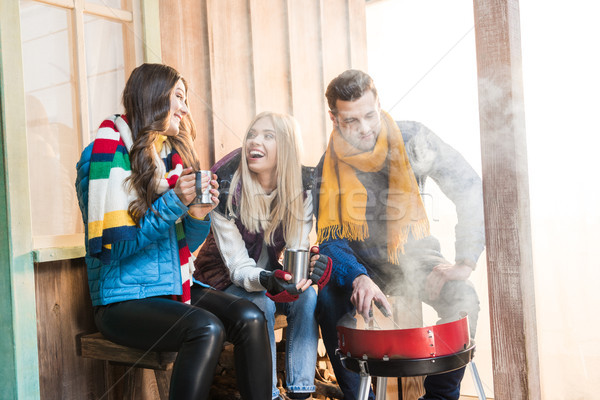 Happy young friends drinking hot tea and grilling meat on porch Stock photo © LightFieldStudios