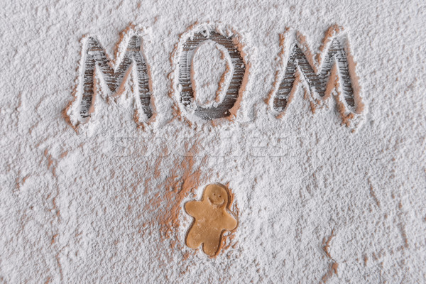 'Top view of uncooked gingerbread man and word mom written in flour, Mothers day concept Stock photo © LightFieldStudios
