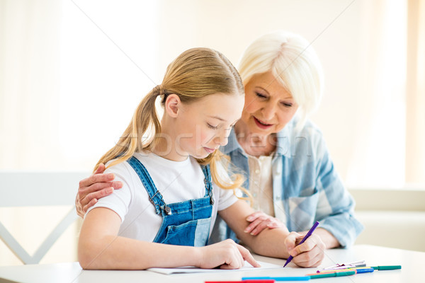 Smiling senior woman and preteen girl drawing together at table Stock photo © LightFieldStudios