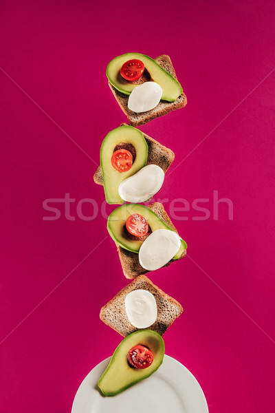 close up view of toasts, avocado pieces, mozzarella cheese and cherry tomatoes falling on plate isol Stock photo © LightFieldStudios