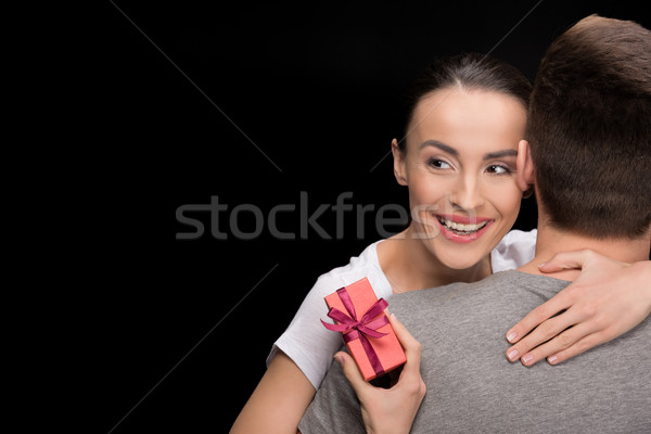 portrait of man hugging happy woman with gift looking away on black, international womens day concep Stock photo © LightFieldStudios