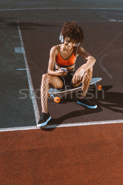 african-american woman on longboard in headphones Stock photo © LightFieldStudios