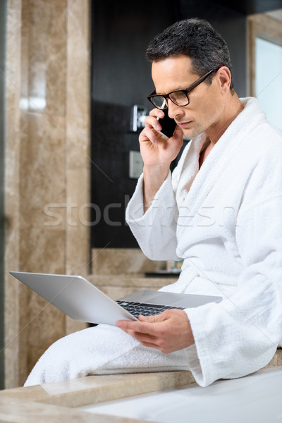 Businessman in bathrobe working with devices Stock photo © LightFieldStudios
