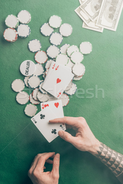 Male hand with poker cards by casino table Stock photo © LightFieldStudios