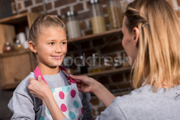 mother putting on apron on daughter Stock photo © LightFieldStudios