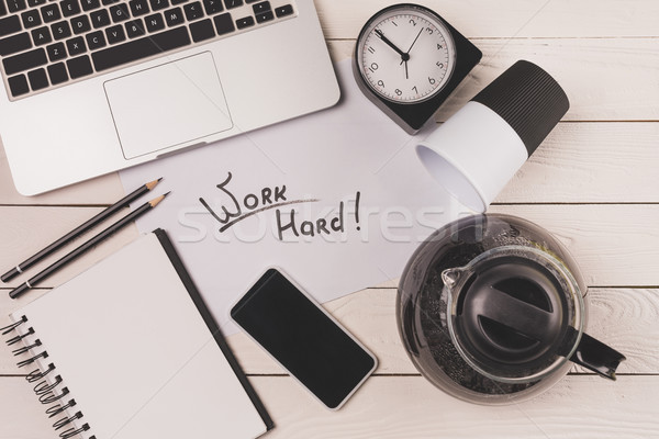 top view of laptop, coffee pot, paper cup, clock, smartphone and inscription work hard at workplace  Stock photo © LightFieldStudios