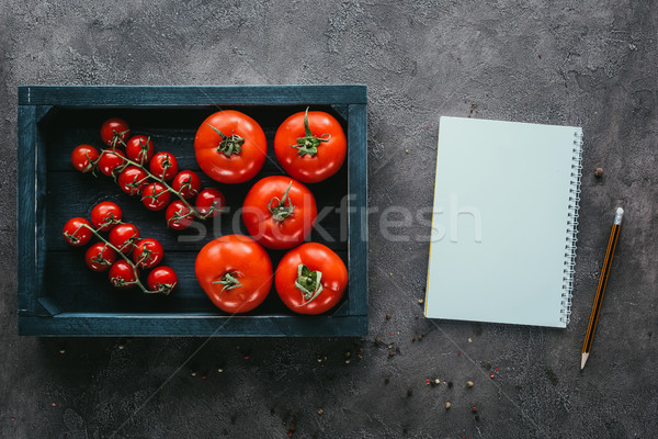 Stock photo: top view of tomatoes in box and notebook on concrete surface