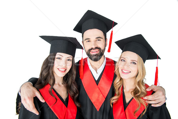 Stock photo: Happy students in academic caps standing embracing and smiling at camera