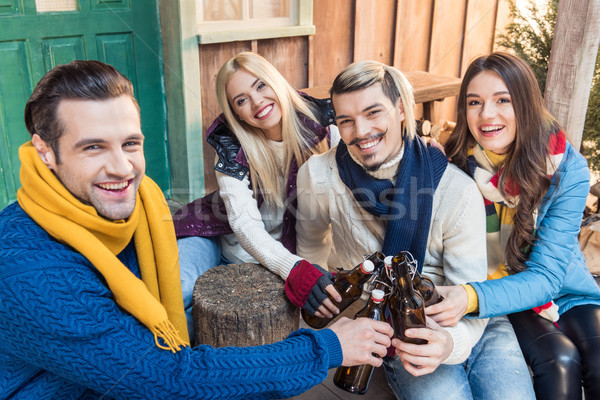 high angle view of friends clinking bottles of beer and looking to camera Stock photo © LightFieldStudios