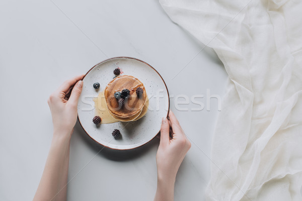 cropped shot of person holding plate with sweet tasty pancakes and fresh berries on grey Stock photo © LightFieldStudios