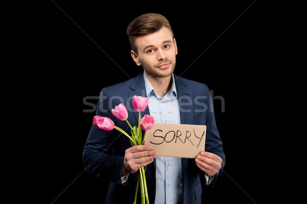 Handsome young man with pink tulips and sorry sign hopefully looking at camera Stock photo © LightFieldStudios