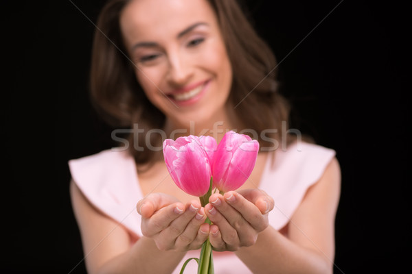 Young smiling woman holding beautiful pink tulips on black, international womens day concept Stock photo © LightFieldStudios