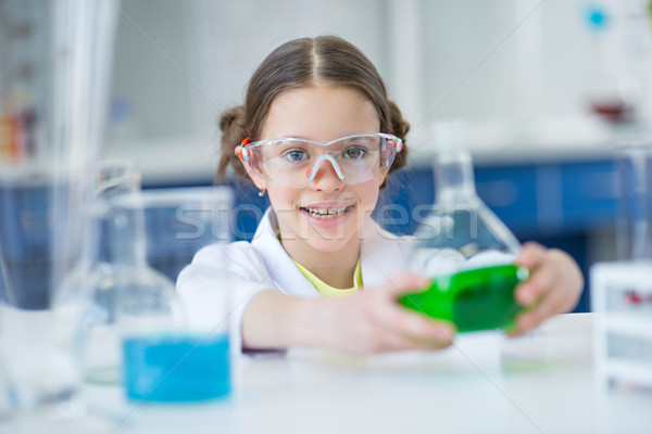Little girl scientist in protective goggles holding flask with reagent in lab Stock photo © LightFieldStudios