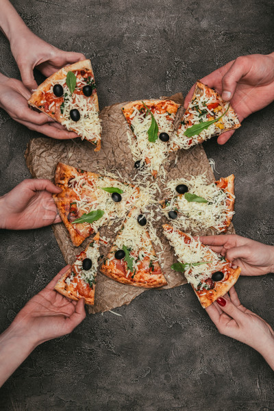 Close-up view of people taking slices of pizza on dark background Stock photo © LightFieldStudios