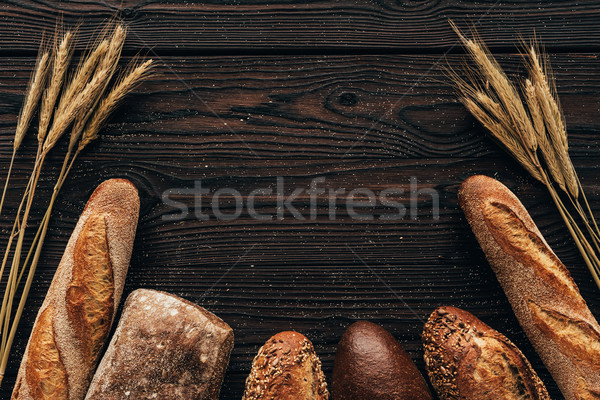 top view of arranged loafs of bread and wheat on wooden surface Stock photo © LightFieldStudios