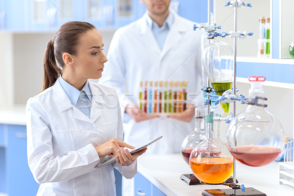 Confident woman scientist holding digital tablet and inspecting reagents in lab Stock photo © LightFieldStudios