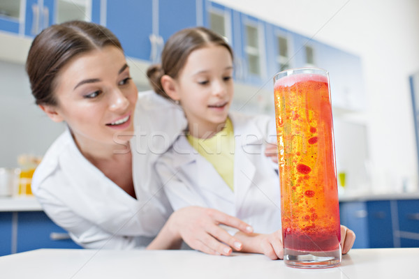 low angle view of excited woman teacher and girl student scientists looking at experimental tube in  Stock photo © LightFieldStudios