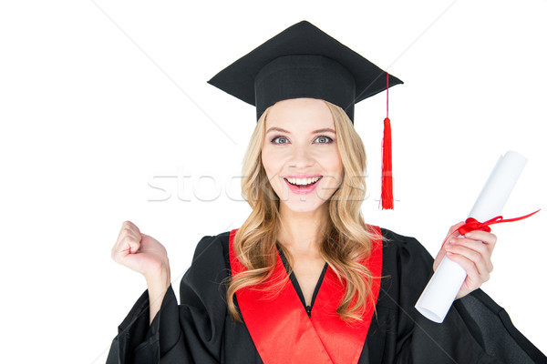 Excited young woman in academic gown and mortarboard holding diploma on white Stock photo © LightFieldStudios