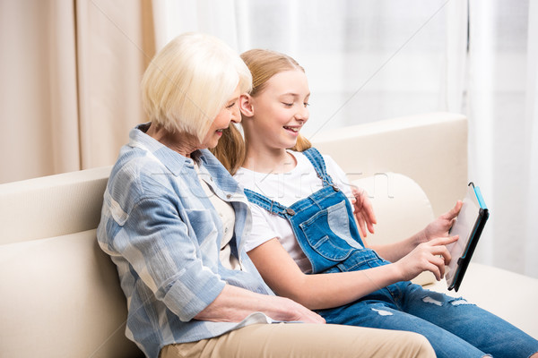 Souriant grand-mère petite fille séance canapé numérique [[stock_photo]] © LightFieldStudios