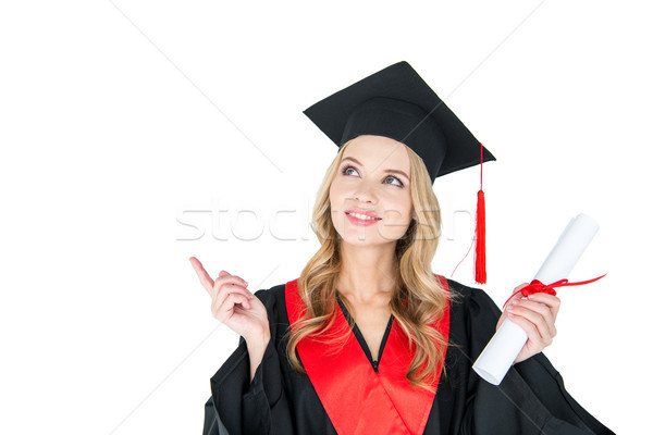 Beautiful young blonde woman in mortarboard holding diploma pointing away with finger Stock photo © LightFieldStudios
