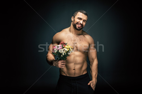 Stock photo: sportive man with bouquet of flowers