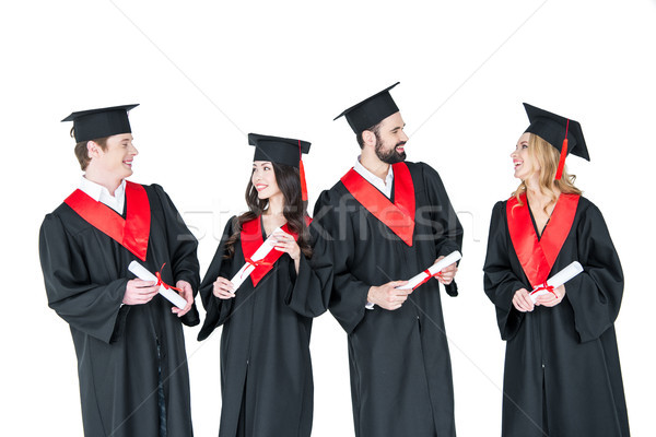 Stock photo: Group of young men and women in graduation gowns and mortarboards holding diplomas