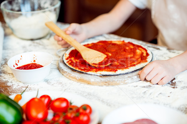 partial view of girl putting tomato sauce on pizza dough Stock photo © LightFieldStudios