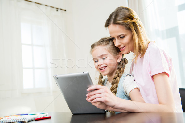 Happy mother and daughter using digital tablet at home Stock photo © LightFieldStudios