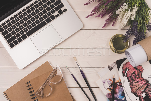 top view of laptop, flowers, blueprint, notebooks with eyeglasses and fashion sketches on wooden tab Stock photo © LightFieldStudios