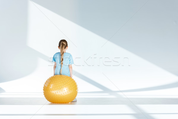 Back view of little girl sitting and exercising on fitness ball Stock photo © LightFieldStudios