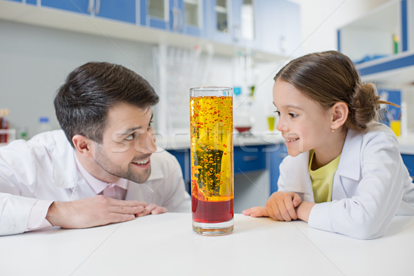 portrait of smiling man teacher and girl student scientists looking at experimental tube in lab Stock photo © LightFieldStudios