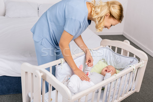 mother looking at baby in crib Stock photo © LightFieldStudios