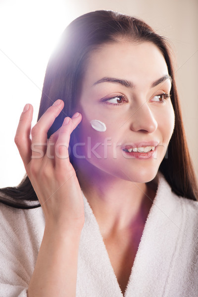 Nő jelentkezik arckrém fiatal vonzó nő fürdőköpeny Stock fotó © LightFieldStudios
