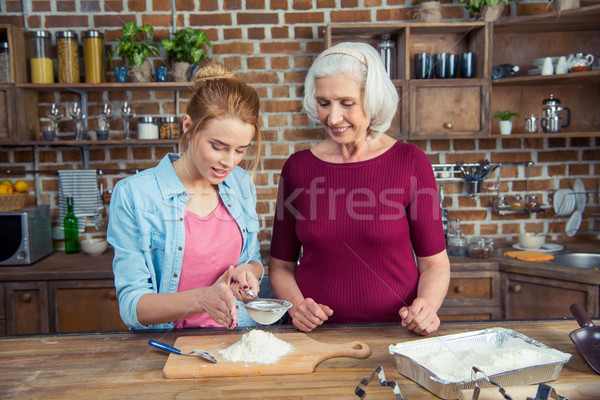 Stock photo: Grandmother and granddaughter sifting flour