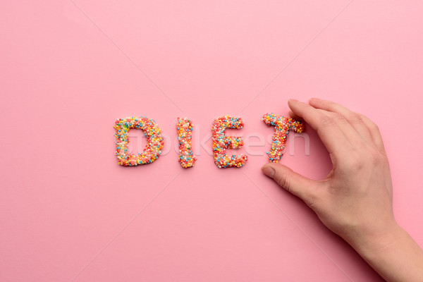 Stock photo: Close-up view of word diet made from sweets and human hand holding letter, healthy eating concept 