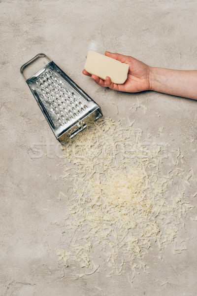 Close-up view of hand holding cheese by grater on light background Stock photo © LightFieldStudios