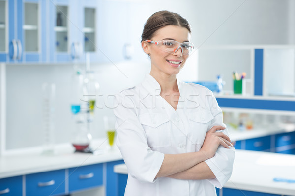 portrait of smiling scientist in white coat and protective glasses in lab Stock photo © LightFieldStudios