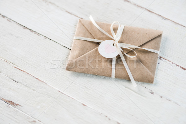 kraft envelope with teg with heart and ribbon on white wooden tabletop, invitation card wedding conc Stock photo © LightFieldStudios