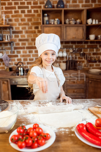 little girl making pizza dough with pizza ingredients on foreground Stock photo © LightFieldStudios
