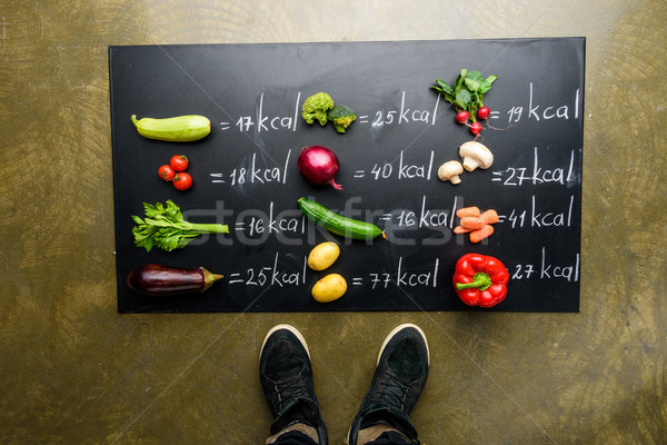 partial view of man standing near fresh vegetables and calories table, healthy lifestyle concept Stock photo © LightFieldStudios