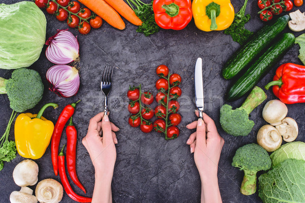 cropped shot of person holding fork and knife above healthy fresh vegetables on black  Stock photo © LightFieldStudios