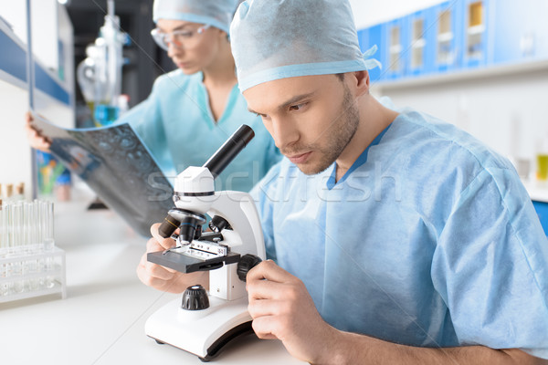side view of surgeon looking through microscope and doctor analyzing x-ray image Stock photo © LightFieldStudios