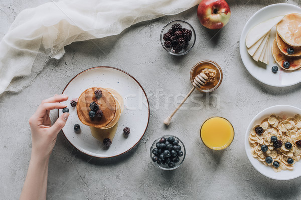 partial top view of person eating delicious homemade pancakes with honey and fruits on grey Stock photo © LightFieldStudios