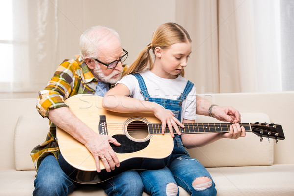 Senior man in eyeglasses teaching cute little granddaughter playing acoustic guitar   Stock photo © LightFieldStudios