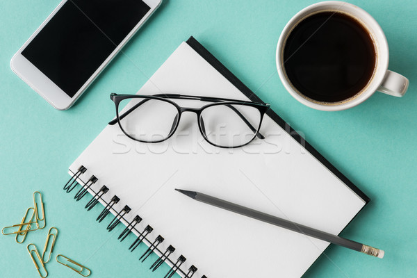 top view of notebook with cup of coffee and smartphone with glasses mock-up, small office home offic Stock photo © LightFieldStudios