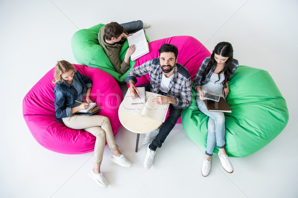 overhead view of students sitting on beanbag chairs and studying in studio on white  Stock photo © LightFieldStudios